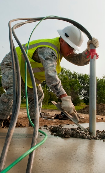 A pavements and equipment operator from the 5th Civil Engineer Squadron flattens cement during a construction project on Minot Air Force Base, N.D., July 15, 2014. CE Airmen are building a search facility for 5th Security Forces Squadron defenders.  (U.S. Air Force photo/Senior Airman Brittany Y. Bateman)