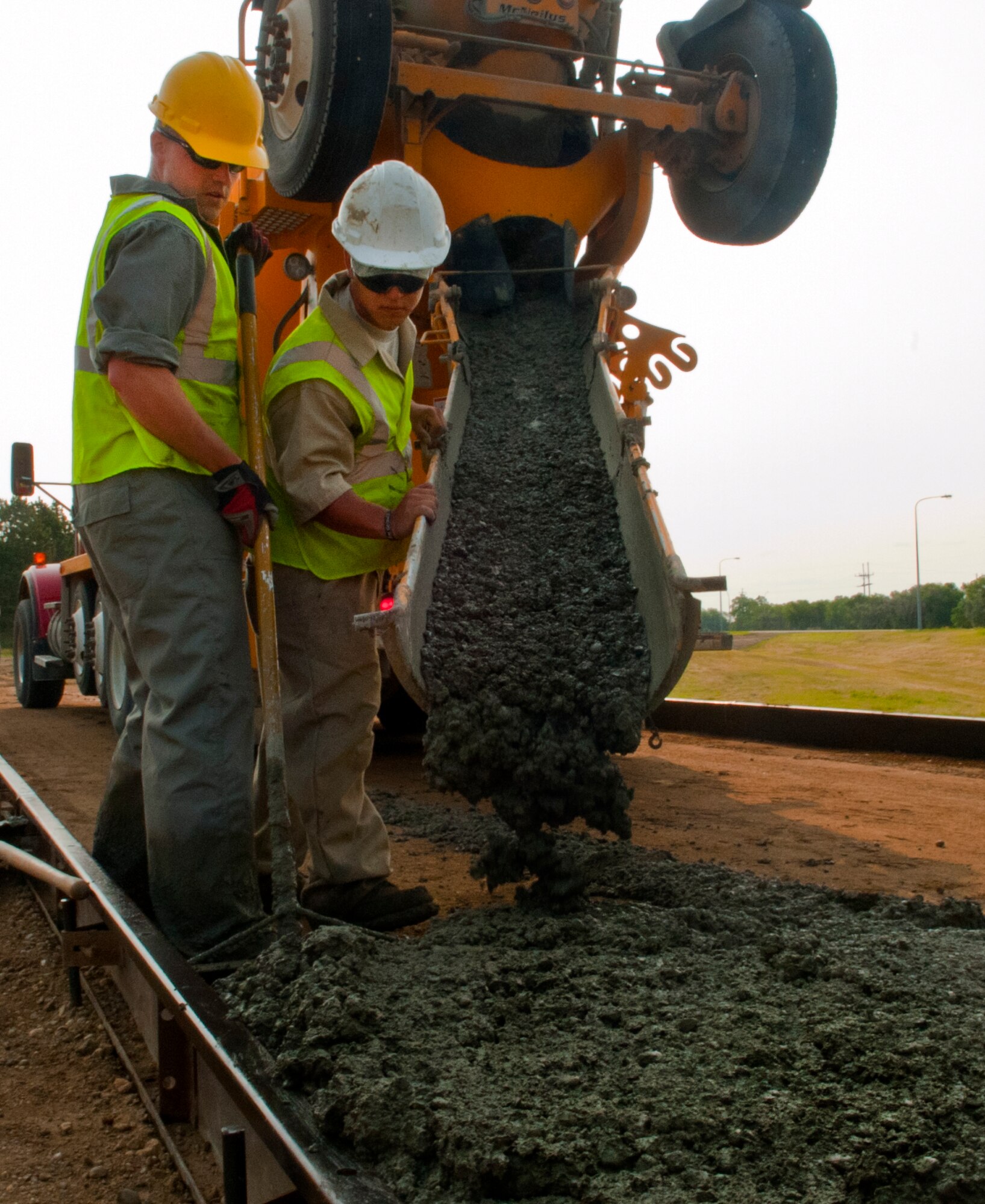 Pavements and equipment operators from the 5th Civil Engineer Squadron pour cement during construction of a new search facility on Minot Air Force Base, N.D., July 15, 2014. In addition to sheltering defenders from harsh weather, the facility also increases commercial vehicle search capabilities with a more robust and secure vehicle search facility. (U.S. Air Force photo/Senior Airman Brittany Y. Bateman)