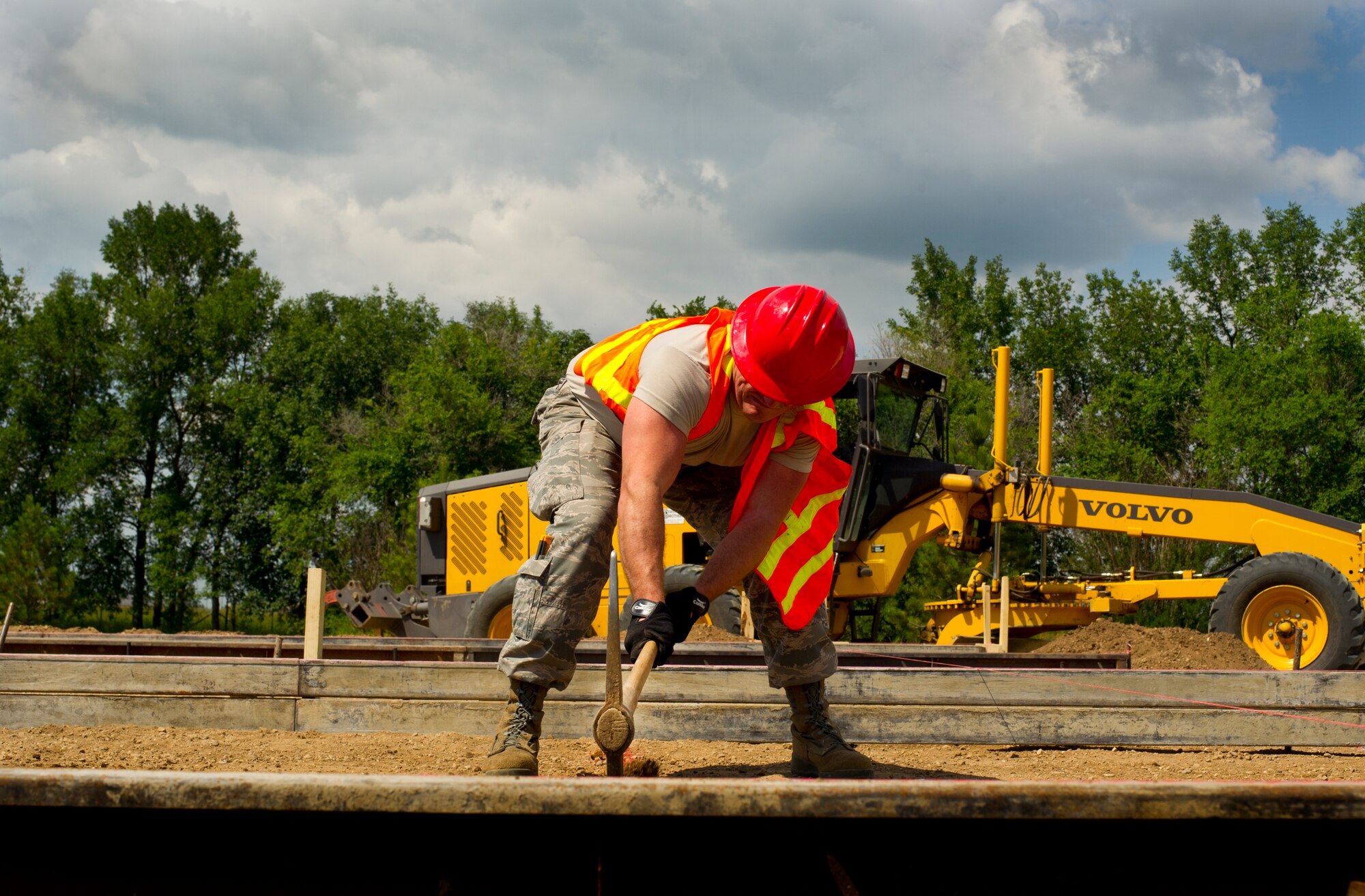 A pavements and equipment operator from the 5th Civil Engineer Squadron uses a pick to loosen dirt during a construction project on Minot Air Force Base, N.D., July 15, 2014. CE Airmen are building a search facility for 5th Security Forces Squadron defenders. (U.S. Air Force photo/Senior Airman Brittany Y. Bateman)
