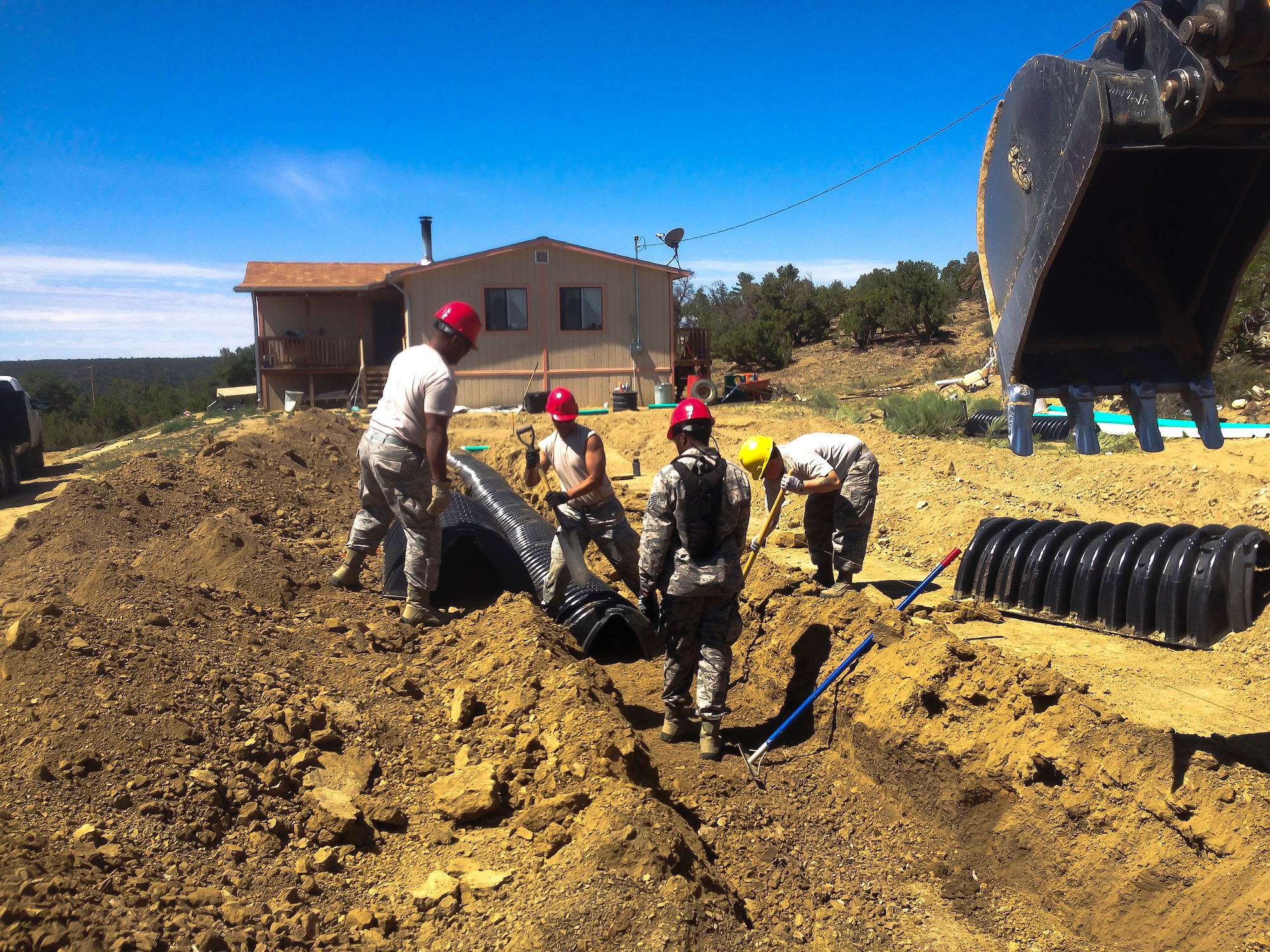 Four members of the 507th Civil Engineer Squadron install new drain for an existing home on the Navajo Nation reservation in Gallup, N.M. in July.  The team partnered with a local charity and constructed homes for impoverished Indians as part of Innovative Readiness Training. (U.S. Air Force photo/1st Lieutenant Christopher Yates)