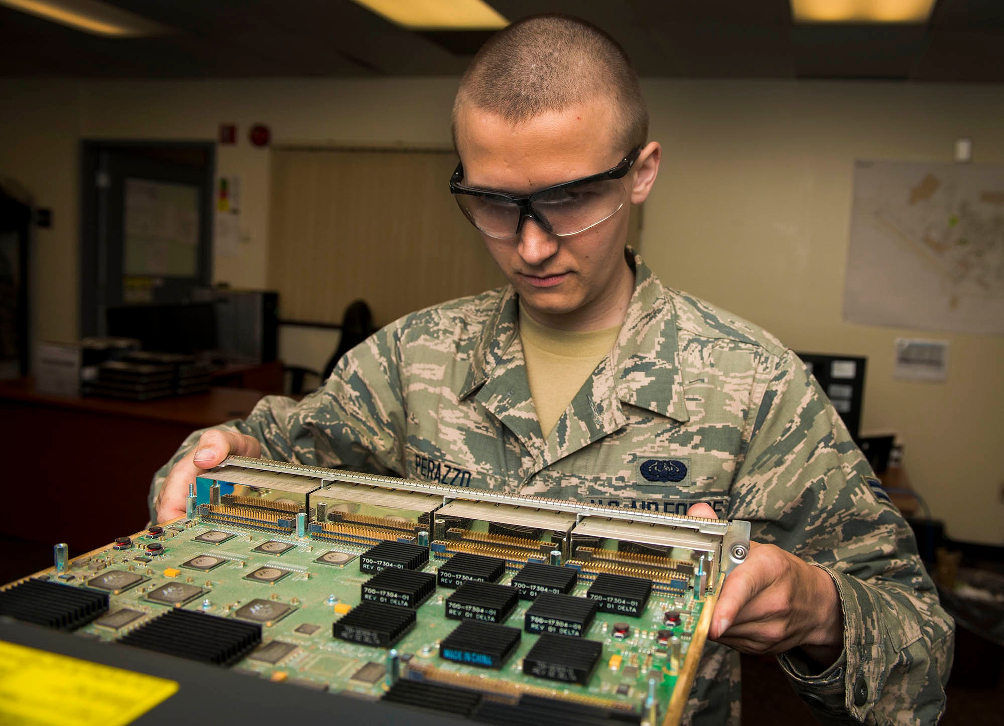 Airman 1st Class Anthony Perazzo, 5th Communications Squadron infrastructure technician, checks the internal components of a piece of equipment for discrepancies in the 5th CS headquarters on Minot Air Force Base, N.D., July 21, 2014. Airmen in the 5th CS infrastructure section maintain, repair and test a variety of mission essential equipment such as computers and area access panels. (U.S. Air Force photo/Senior Airman Stephanie Morris)