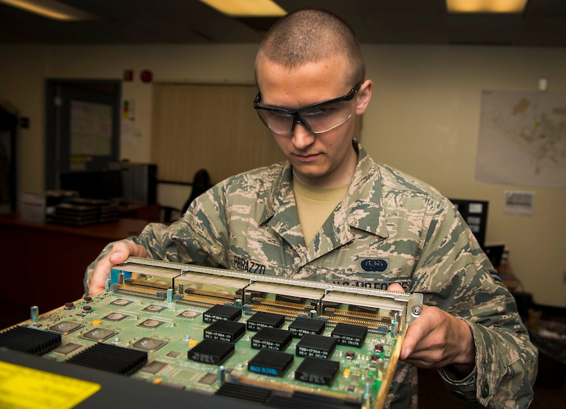 Airman 1st Class Anthony Perazzo, 5th Communications Squadron infrastructure technician, checks the internal components of a piece of equipment for discrepancies in the 5th CS headquarters on Minot Air Force Base, N.D., July 21, 2014. Airmen in the 5th CS infrastructure section maintain, repair and test a variety of mission essential equipment such as computers and area access panels. (U.S. Air Force photo/Senior Airman Stephanie Morris)