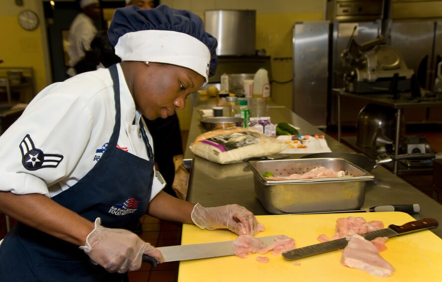 Airman 1st Class Esther Jeremiah, 436th Force Support Squadron slices an uncooked chicken breast July 24, 2014, at the Patterson Dining Facility on Dover Air Force Base, Del. Jeremiah and three team members representing the 436th Force Support Squadron, competed against a team from the Air Force Mortuary Affairs Operations, Dover AFB, in the Dover Iron Chef competition. (U.S. Air Force photo/Roland Balik)