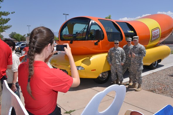 Airmen snap a photo with the Oscar Meyer Weiner Mobile, which visited the Kirtalnd Commissary July 25. The promotion gave free hot dogs and other items to customers.  (Photo by Todd Berenger)