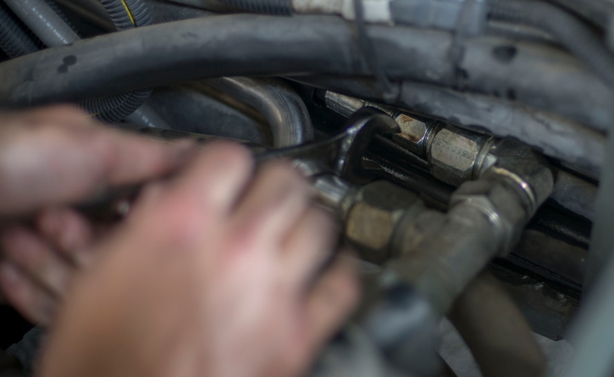 U.S. Air Force Tech. Sgt. Jason Zollman, 23d Logistics Readiness Squadron NCO in charge of special purpose maintenance, unscrews a hydraulic pipe on an aircraft loader at Moody Air Force Base, Ga., July 28, 2014. Zollman says the loader is considered a mission-critical vehicle because only two are assigned to Moody. (U.S. Air Force photo by Airman 1st Class Dillian Bamman/Released)