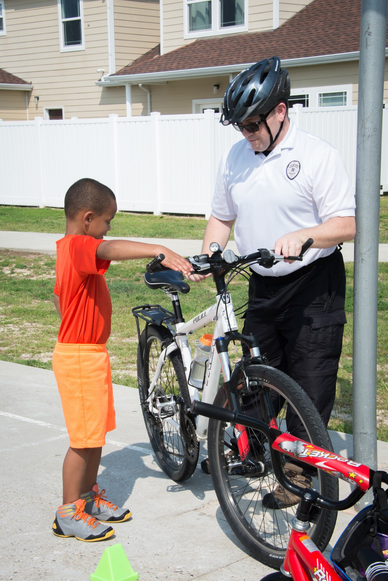 Officer Warren Breckenridge, 81st Security Forces Squadron, gives a bike safety lesson to the son of Capt. Jimmy Griffith, 333rd Training Squadron, during the 81st SFS Bike Rodeo July 25, 2014, at the Forest City Community Center, Keesler Air Force Base, Miss.  The event, hosted by 81st SFS and Forest City Community Services, was held for Keesler families to perform and promote safety checks for bikes and car seats.  (U.S. Air Force photo by Marie Floyd)