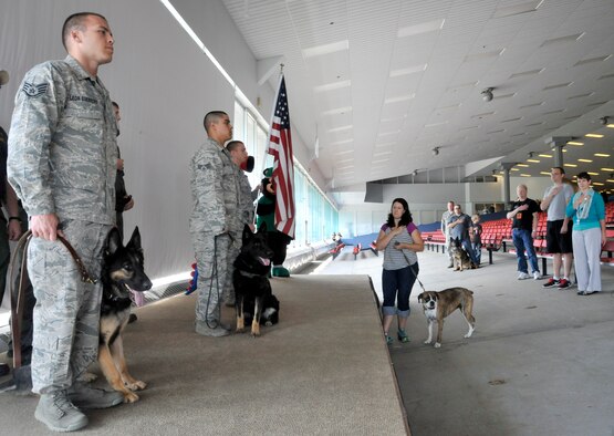 Airmen from the 92nd Security Forces Squadron military working dog section stand at attention during the opening ceremony at the Canines vs. Cancer event in Post Falls, Idaho, July 19, 2014. The MWD section provided a demonstration to attendees and participated in a ceremonial lap during a 5k prior to opening ceremonies. The Canines vs. Cancer mascot, Lucky, is named after a Fairchild MWD. (U.S. Air Force photo by Senior Airman Mary O'Dell/Released)