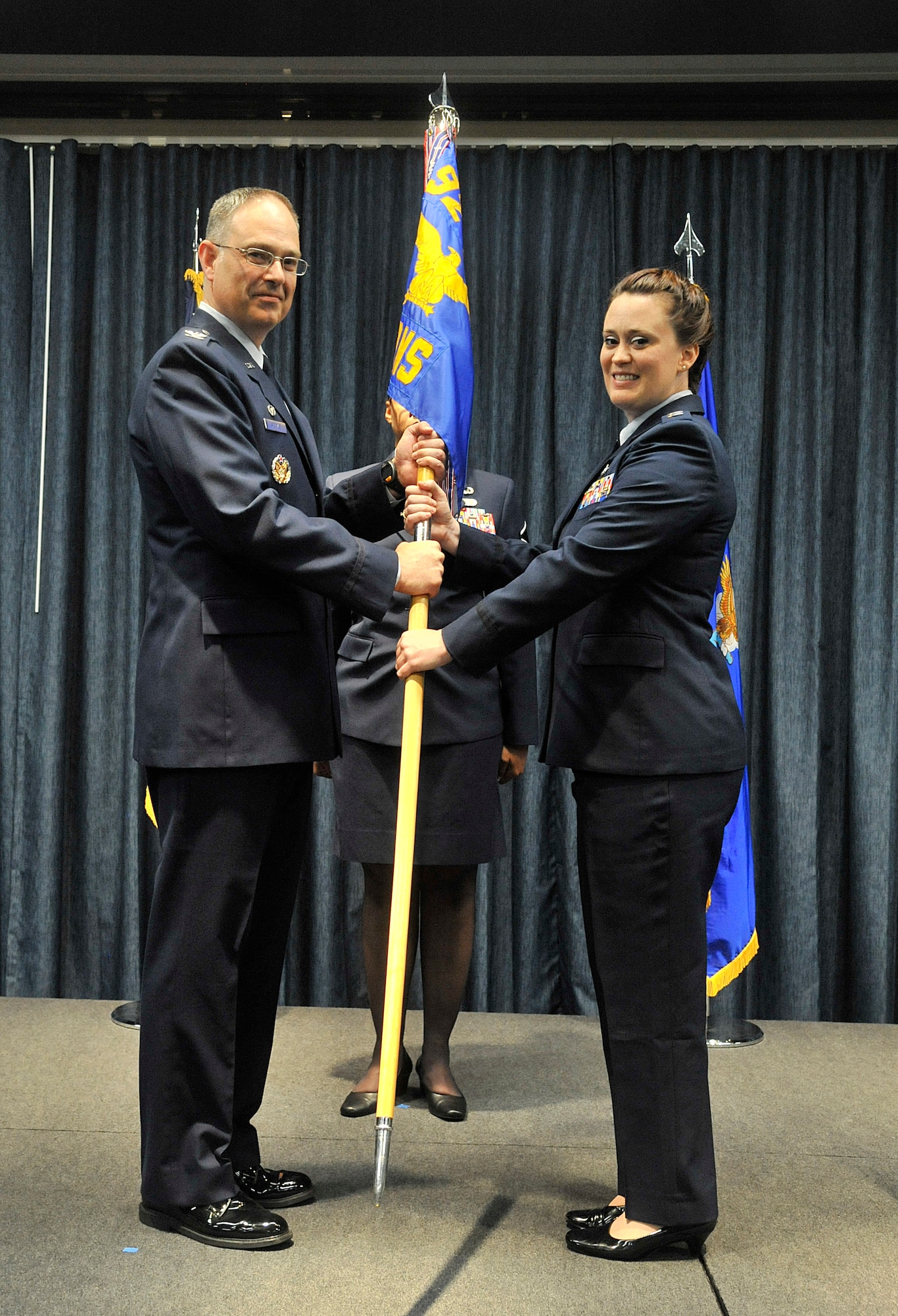 Col. David Stookey presents the 92nd Communications Squadron guidon to Capt. Kathryn Hinds during a change of command ceremony at Fairchild Air Force Base, Washington, July 23, 2014. Stookey is the 92nd Mission Support Group commander and Hinds is the new 92nd CONS commander. (U.S. Air Force photo by Senior Airman Mary O'Dell/Released)