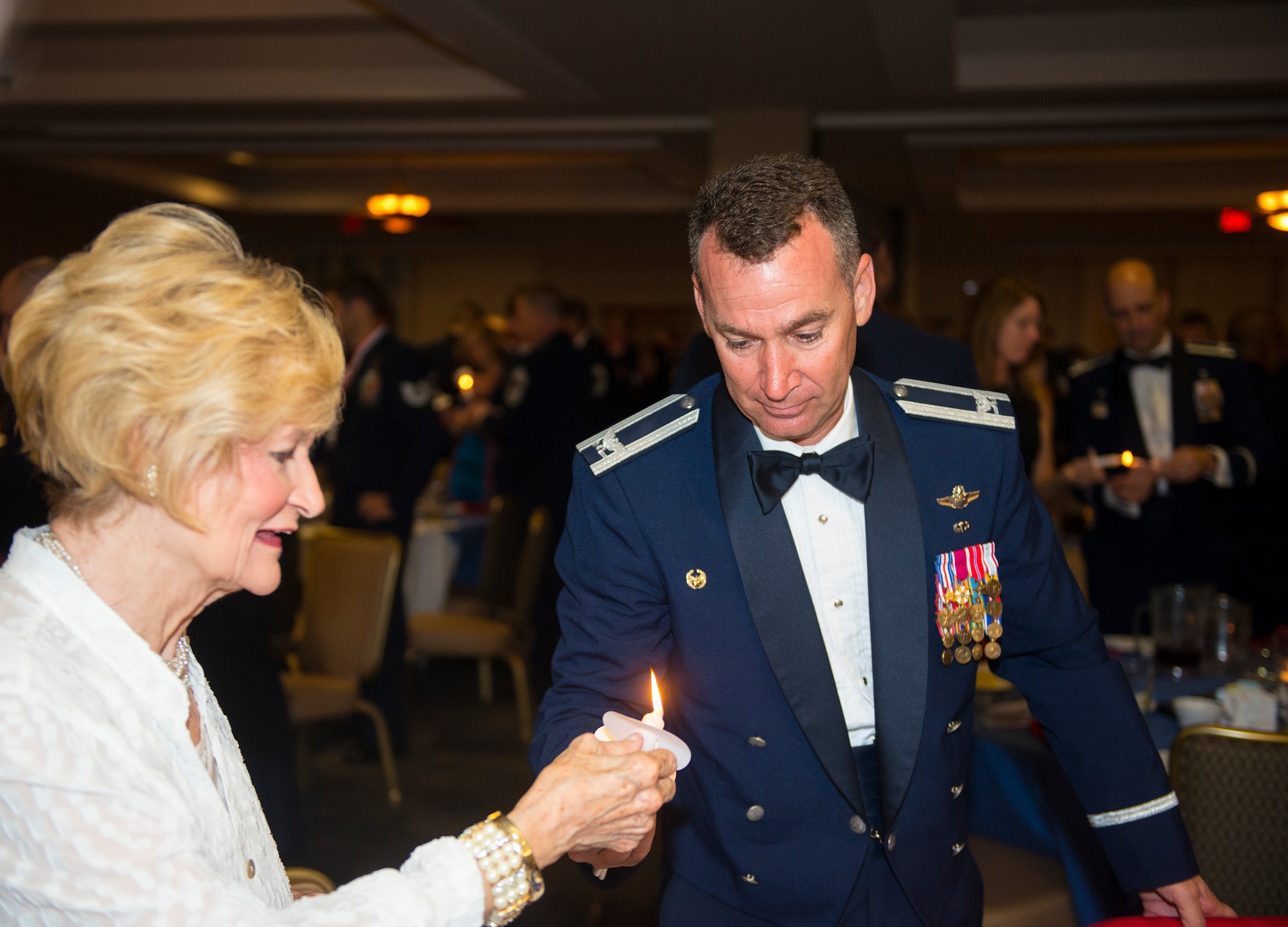 U.S. Air Force Col. Chad Franks, 23d Wing commander, and Dr. Lucy Green light their candles during a senior NCO induction ceremony at Moody Air Force Base, Ga., July 25, 2014. At this induction ceremony, the lighting of the candle symbolized knowledge, success, motivation and ideas. (U.S. Air Force photo by Airman 1st Class Ceaira Tinsley/Released)