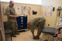 Master Sgt. Nathan Carlson, 219th Security Forces Squadron health technician, touches his toes to locate pain in his back at Minot Air Force Base, N.D., May 22, 2014. Locating and testing pain levels are the first steps in battlefield acupuncture before inserting the studs into the ear. (U.S. Air Force photo/Airman 1st Class Sahara L. Fales)