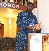 Naval Health Clinic Charleston Petty Officer 2nd Class Anthony Houston, places non-perishable food items recently donated by NHCC staff members in a food collection barrel in the NHCC atrium at Joint Base Charleston, S.C. NHCC is participating in the "Feds Feed Families" campaign to collect food and help combat hunger in our local communities. NHCC has one of several food collection barrels placed at commands around the Weapons Station. Last year the Weapons Station collected more than 3,240 pounds of food. This year’s goal is to increase that amount by 10 percent. While food banks typically see large amounts of food on their shelves over the winter months, donations typically trail off after the holidays are over. Personnel wishing to donate have until the end of August to place non-perishable food items in the designated box in the atrium. Monetary donations may be made through the Religious Offerings Fund at the Weapons Station chapel. Each dollar is the equivalent to five pounds of food. (U.S. Navy Photo/Petty Officer 3rd Class Caralyn/Mulyk)

