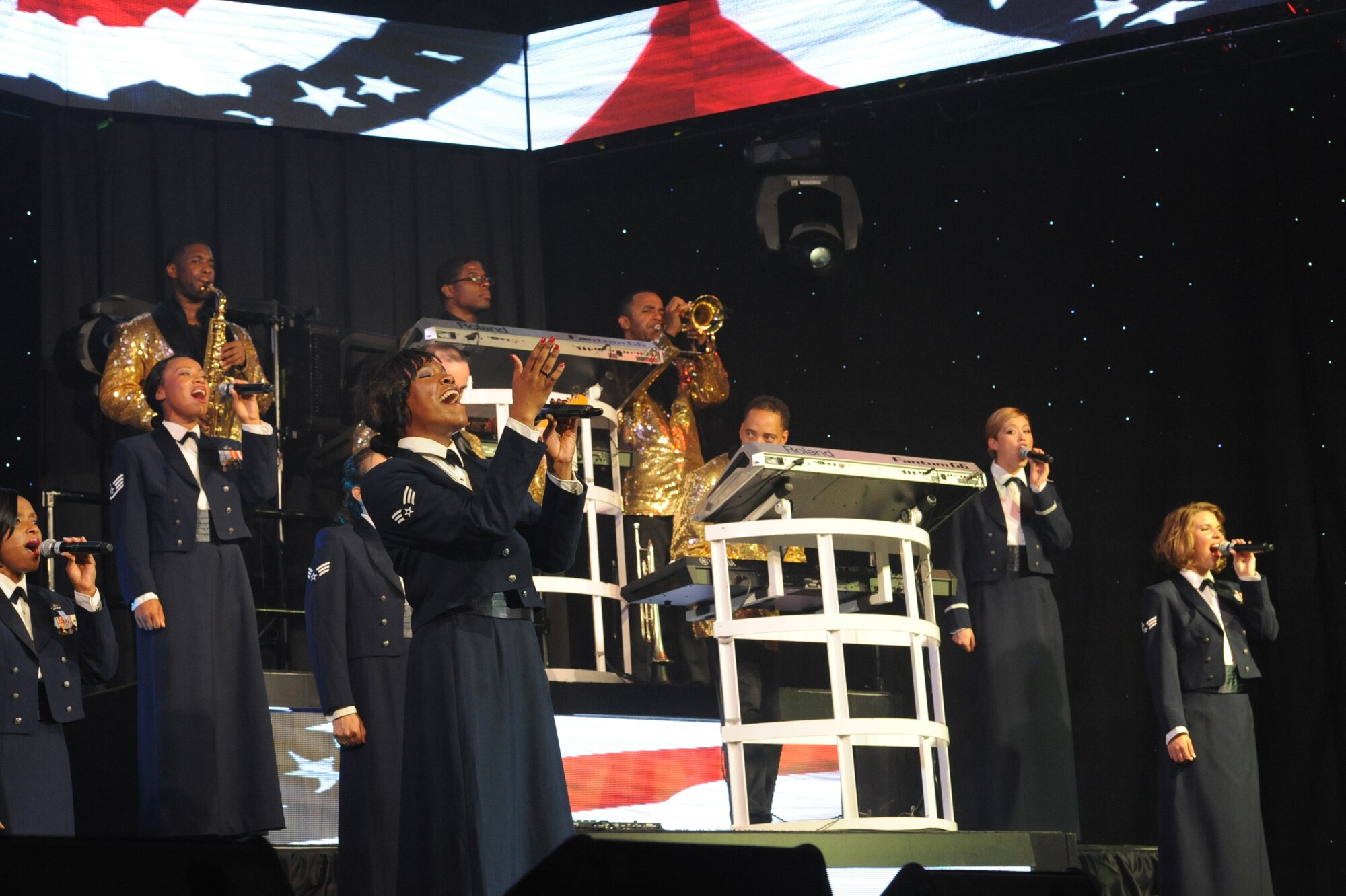 U.S. Air Force Senior Airman Nia Newton, Tops in Blue vocalist, leads the women's ensemble in a song dedicated to American pride at the Keystone Theater on Kadena Air Base, Okinawa, Japan, July 27, 2014. Tops in Blue is an Air Force global entertainment unit dedicated to providing entertainment to the Air Force family. (U.S. Air Force photo by Airman 1st Class Zackary A. Henry/Released)