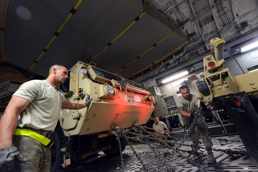 U.S. Air Force Senior Airman Cody Daluz, left, and U.S. Air Force Tech. Sgt. Christopher Foster, center, wait for U.S. Air Force Senior Airman Jerry Hullette, right, to finish securing a cable to a heavy expanded mobility tactical truck on Bagram Airfield, Afghanistan, July 20, 2014. Daluz, Foster and Hullette, cargo processors, are assigned to the 455th Expeditionary Aerial Port Squadron.