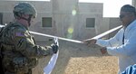 Army Col. Andy Hall, commander of the Georgia Army National Guard's 648th Maneuver Enhancement Brigade, prepares to cut the ribbon to officially open a simulated U.S.-built Afghan school while a role-playing Afghan community member looks on during a Division West-led training event at Fort Hood, Texas, Jan. 6, 2012. Division West's 120th Infantry Brigade trains Army National Guard and Army Reserve Soldiers for deployment by replicating events units may experience overseas.