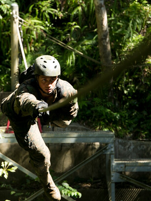 Cpl. Chance Sweatt, a Columbia, South Carolina, native, demonstrates how to properly cross the commando crawl obstacle July 20 during the Combat Endurance Course at the Jungle Warfare Training Center on Camp Gonsalves. The obstacle required students to tie a harness and crawl across a rope over a pond. Sweatt is an instructor at JWTC and infantryman with 1st Bn., 3rd Marine Division, III Marine Expeditionary Force. (U.S. Marine Corps photo by Lance Cpl. Brittany A. James/released)  