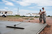 Staff Sgt. Travis Hendell, 911th Civil Engineer Squadron, evens the cement pad as Staff Sgt. Michael Butler, 50 Civil Engineer Squadron, looks on July 25, 2014, at Schriever Air Force Base, Colo.  Airmen with 50 and 911 CES worked together for two weeks on various tasks such as pump replacement for fire suppression, water pump service, road sign replacement, office renovations, heating, ventilation and air conditioning and electrical work orders and various other trouble tickets. (U.S. Air Force photo/Staff Sgt. Julius Delos Reyes)