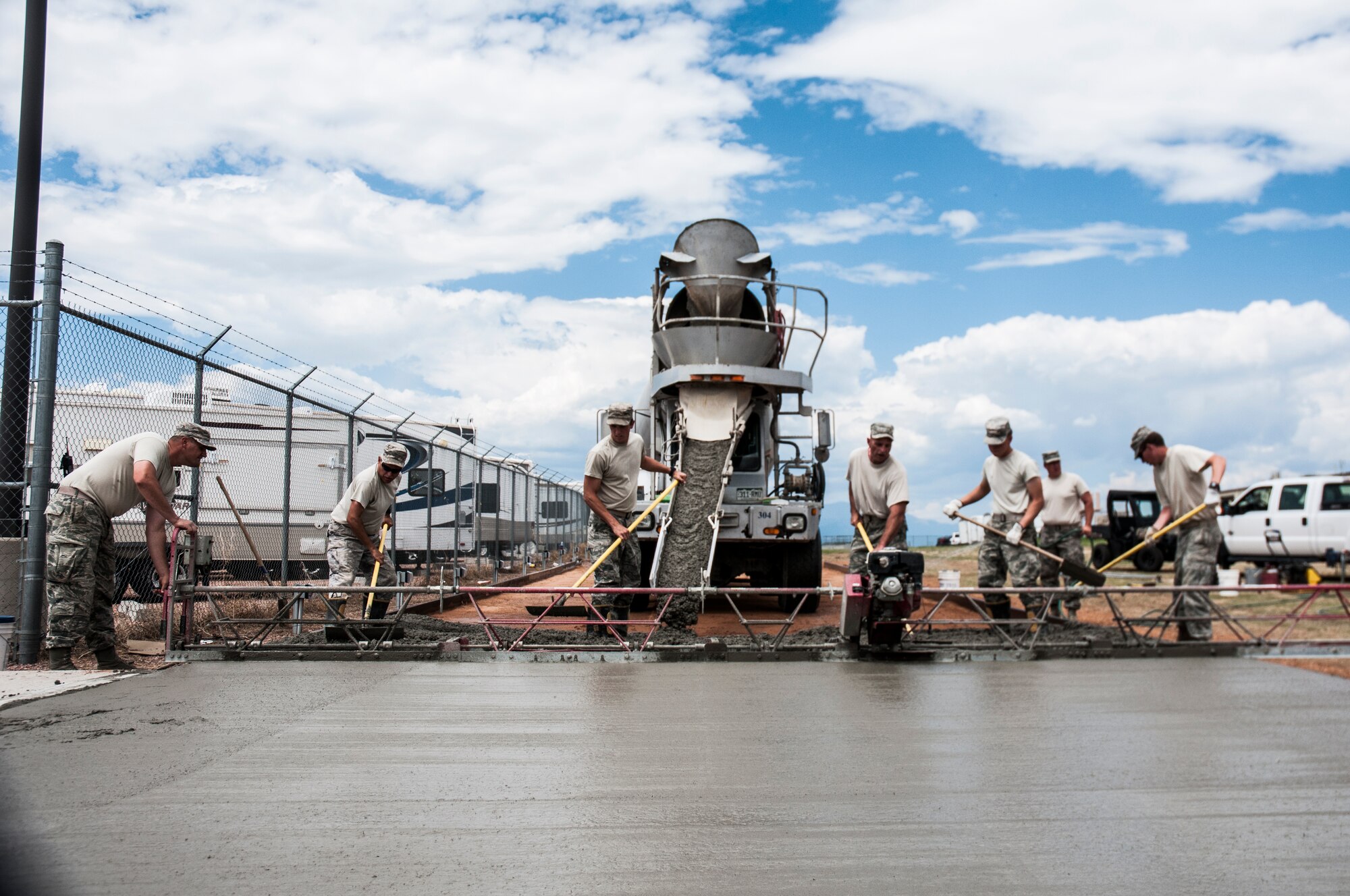 Airmen with the 50th and 911th Civil Engineer Squadron work together to complete a cement pad for the Outdoor Recreation recreational vehicle parking lot July 25, 2014, at Schriever Air Force Base, Colo. Thirty-two 911 CES reservists with eight different Air Force Specialty Codes, such as electricians, utilities, heavy equipment operators, operations and management, integrated into 50 CES shops and worked alongside Schriever Airmen on various 50 CES projects. (U.S. Air Force photo/Staff Sgt. Julius Delos Reyes)