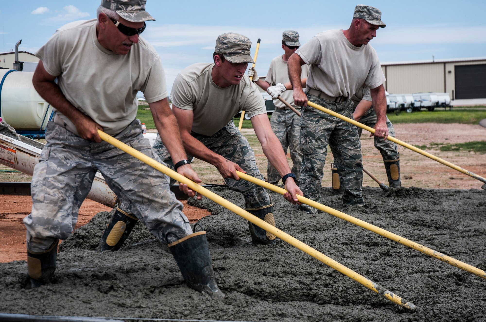 Airmen with 50th and 911th Civil Engineer Squadron work together to complete a cement pad for the Outdoor Recreation recreational vehicle parking lot July 25, 2014, at Schriever Air Force Base, Colo. Thirty-two 911 CES reservists with eight different Air Force Specialty Codes, such as electricians, utilities, heavy equipment operators, operations and management, integrated into 50 CES shops and worked alongside Schriever Airmen on various 50 CES projects. (U.S. Air Force photo/Staff Sgt. Julius Delos Reyes)
