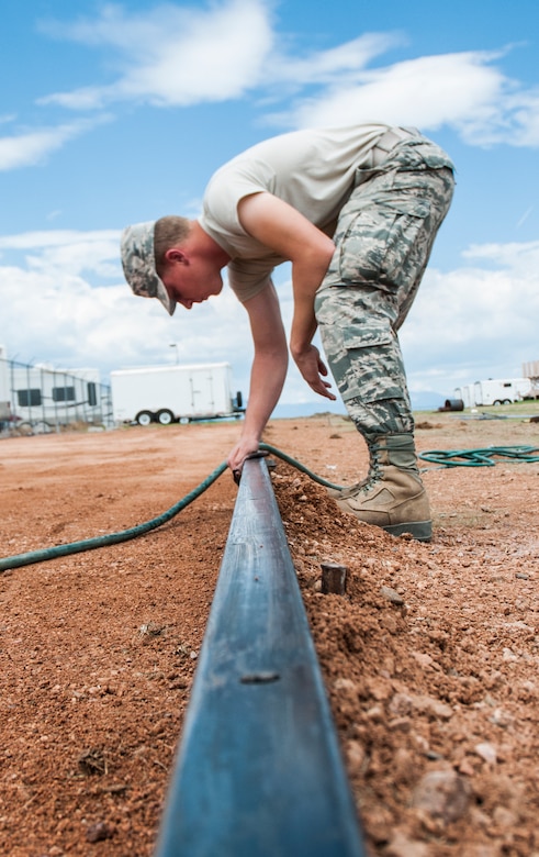 Airman 1st Class Christopher Anderson, 50th Civil Engineer Squadron, cleans the barrier for a cement pad July 25, 2014, at Schriever Air Force Base, Colo. Airmen with 50 CES worked on various projects with the 911th Civil Engineer Squadron, a unit from Pittsburgh Air Reserve Station, Pennsylvania, for two weeks as part of the 911 CES’s annual requirement. (U.S. Air Force photo/Staff Sgt. Julius Delos Reyes)