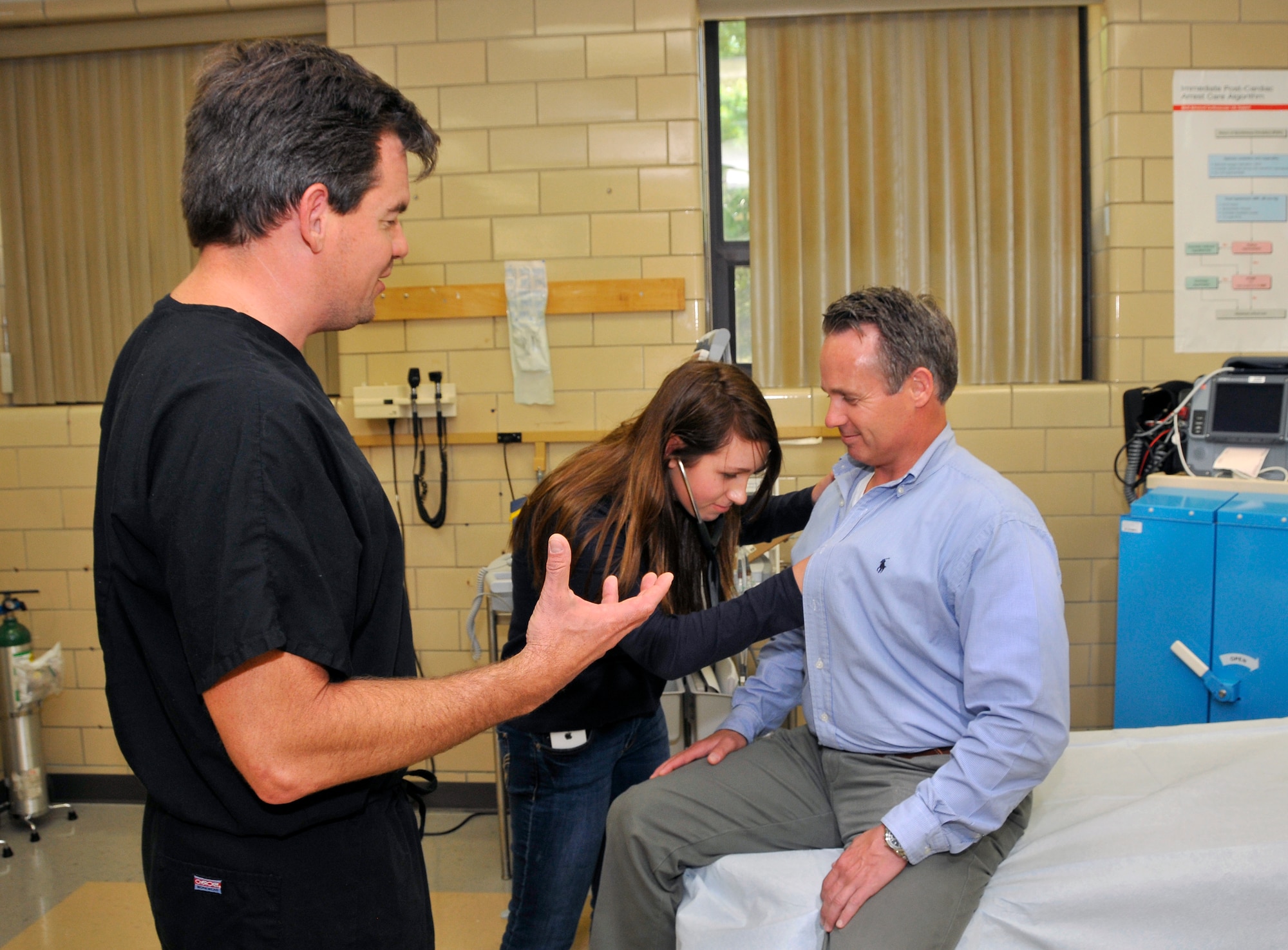 Hannah Jenkins, daughter of Aerospace Testing Alliance (ATA) Industrial Hygiene and Risk manager Mark Jenkins had the opportunity to practice her medical skills at the dispensary during Job Shadow Day. Pictured is Hannah using a stethoscope to listen to her dad’s heartbeat as Dr. Rob Tessier, left, provides instructions. 