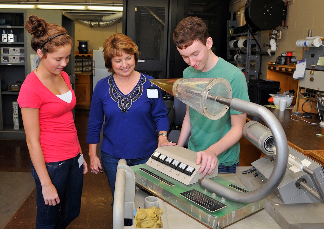 Alexis Loman and Samuel Oliver spent the day shadowing their mom, Susan Loman, group lead for the Data Processing and Analysis Development and Support Group, at the von Kármán Facility. Here Susan shows her son and daughter a balance simulator in the VKF lab.
