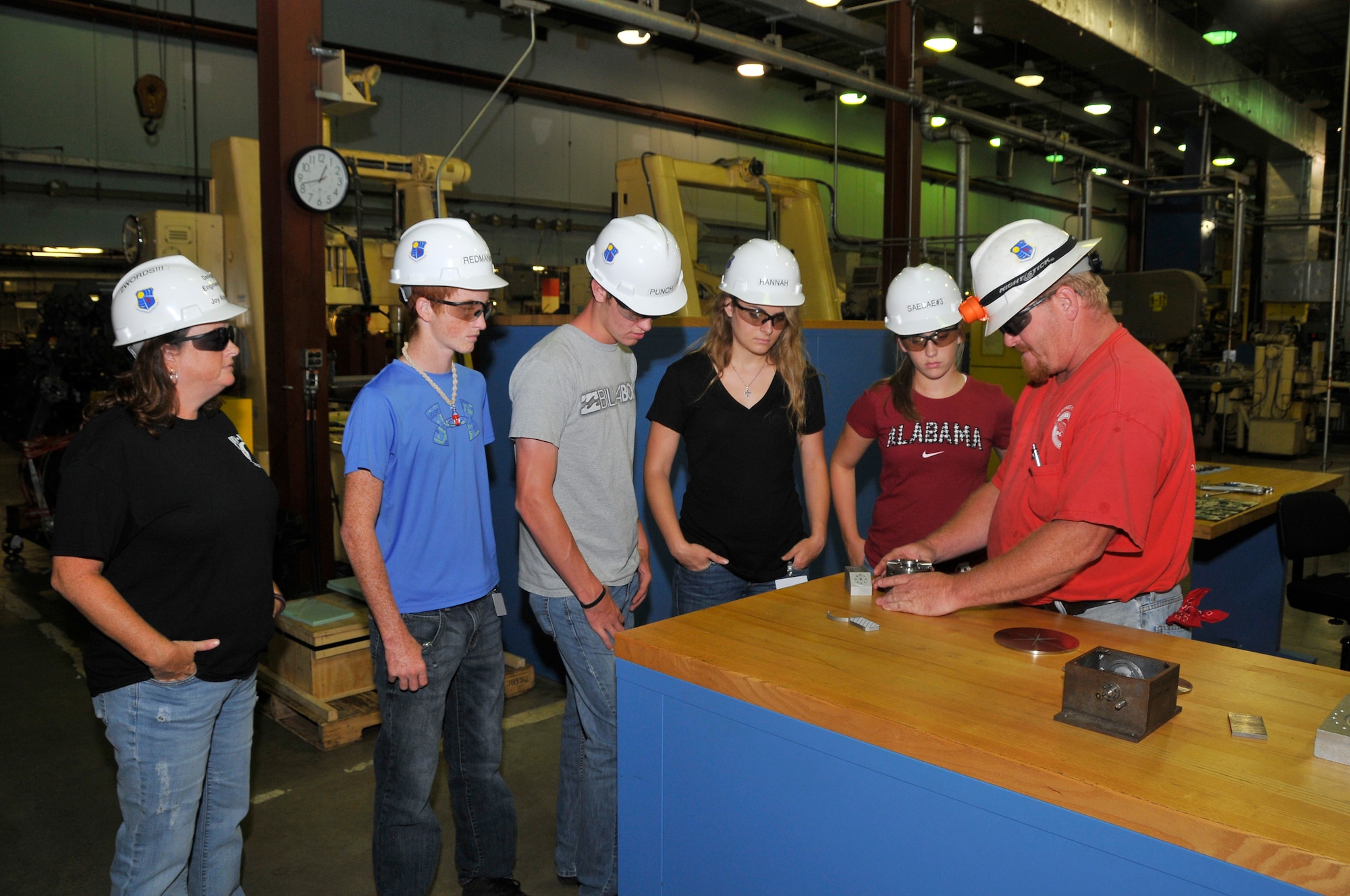 Arnold Engineering Development Complex (AEDC) personnel Joy and Dusty Rogers show a group of four Job Shadow Day participants around the Model and Machine Shop. Pictured are Zach Rogers, Peyton Punch, Hannah Newman and Sarah Petty watching as Dusty demonstrates how the parts to a two-piece water-cooled sting adapter work together. 