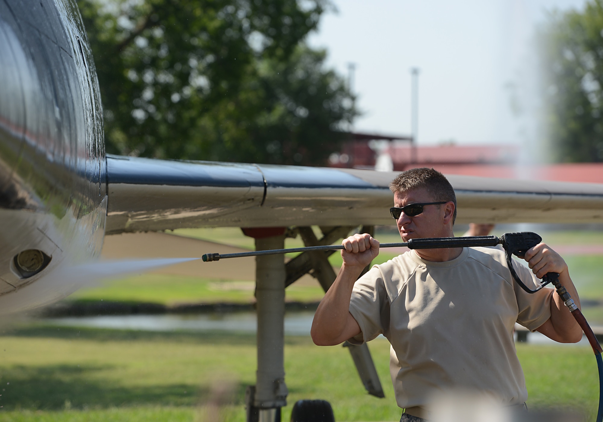 Chief Master Sergeant Bryan Blansett, 138th Civil Engineering Squadron Chief,  power washes the fuselage of an F-100 static display aircraft at the Tulsa Air National Guard base, Tulsa Okla., 29 July 2014.  Members of the 138th FW Chiefs Council gathered to wash the static aircraft in an effort to keep them looking nice for public display.  (U.S. National Guard photo by Senior Master Sgt.  Preston L. Chasteen/Released)