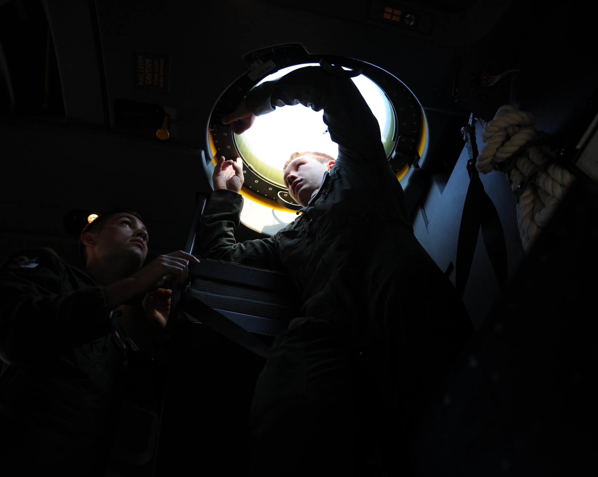 U.S. Air Force Capt. Tyler Comte, 39th Airlift Squadron co-pilot, looks on as Airman 1st Class Jacob Betts, 40th Airlift Squadron loadmaster, installs a window in the ceiling of a C-130J Super Hercules July 23, 2014, at Dyess Air Force Base, Texas. During a training exercise, Betts used the bubble-shaped window to watch an F-16 Fighting Falcon and relay information over a headset to his fellow crewmembers. (U.S. Air Force photo by Airman 1st Class Kedesha Pennant/Released)