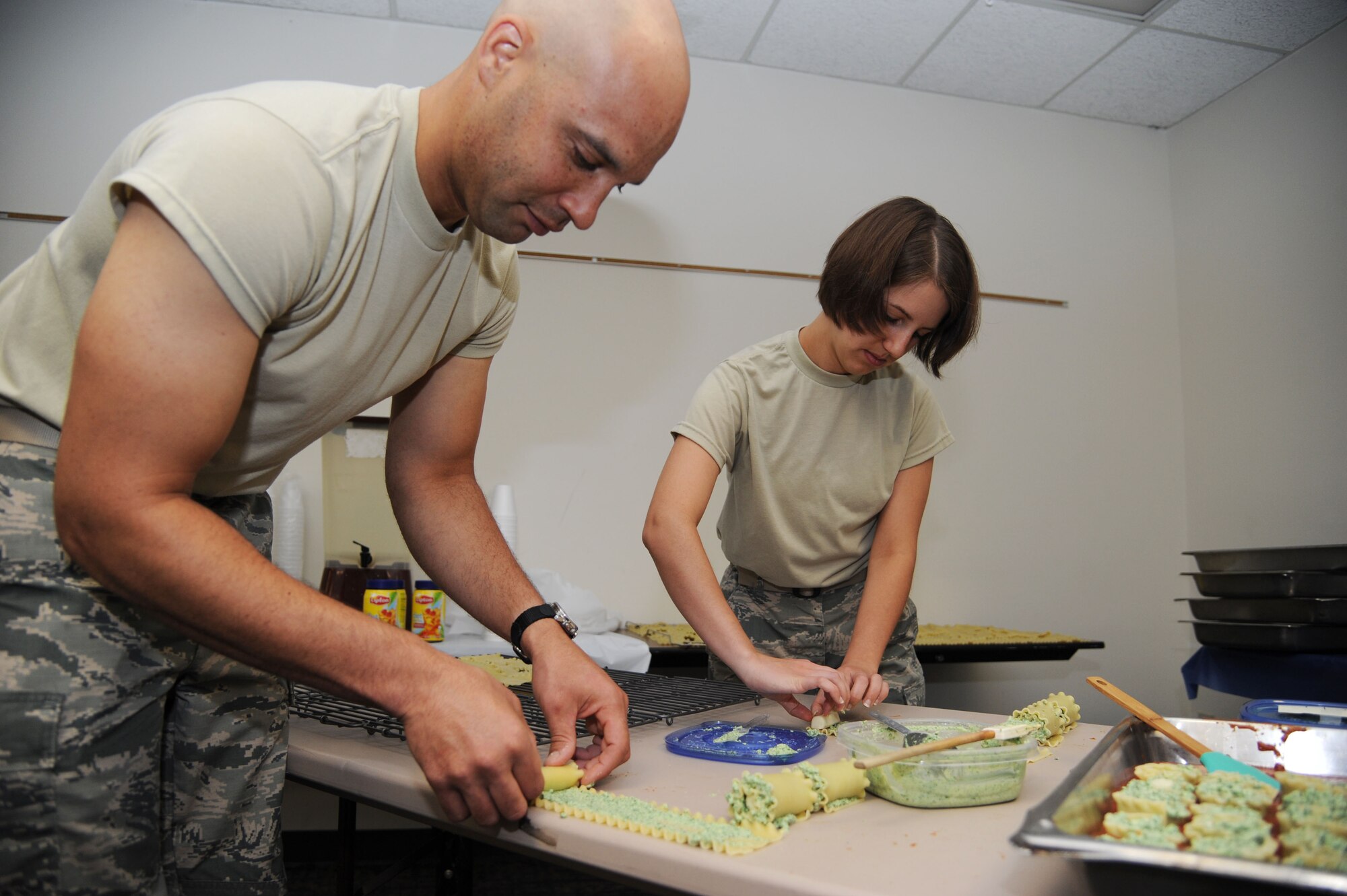 VANCE AIR FORCE BASE, Okla. -- Senior Airman Clarence Kalik-Underwood, the 71st Flying Training Wing command chief’s executive assistant, and 2nd Lt. Isabel Crump, the 71st FTW deputy chief of Public Affairs, prepare pasta pinwheels for the monthly Singles' International Gourmet Meal Opportunity event at the Community Chapel Activities Center July 28. SIGMO is a free, home-cooked meal for single Airmen, single parents, unaccompanied Airmen of all ranks and the families of deployed members. (U.S. Air Force photo/Staff Sgt. Nancy Falcon)
