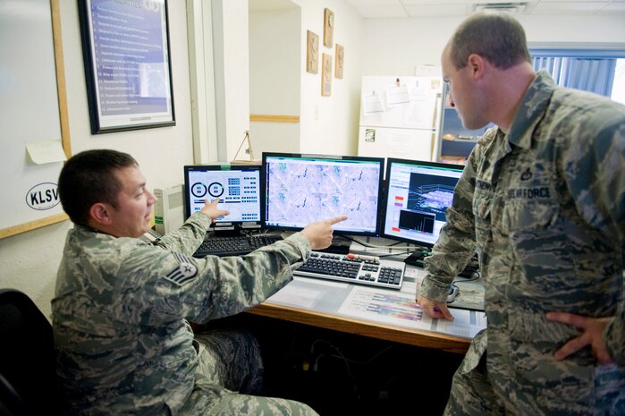 Staff Sgt. Jarad Guerrero-Salinas, 57th Operations Support Squadron shift supervisor, and Master Sgt. Adam D'Anthony, 57th OSS airfield weather support NCO in charge, discuss a thunderstorm and its severity, July 28, 2014, at Nellis Air Force Base, Nev. Weather forecasters are tasked with resource protection, which includes watches, warnings and advisories for the base. (U.S. Air Force photo by Airman 1st Class Rachel Loftis)