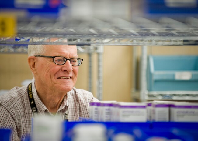Retired U.S. Army Maj. Jim Duggins, 99th Medical Support Squadron volunteer, looks for medication on a shelf, July 30, 2014, at the satellite pharmacy on Nellis Air Force Base, Nev. The pharmacies on base fill approximately 830,000 prescriptions every year. (U.S. Air Force photo by Senior Airman Jason Couillard)