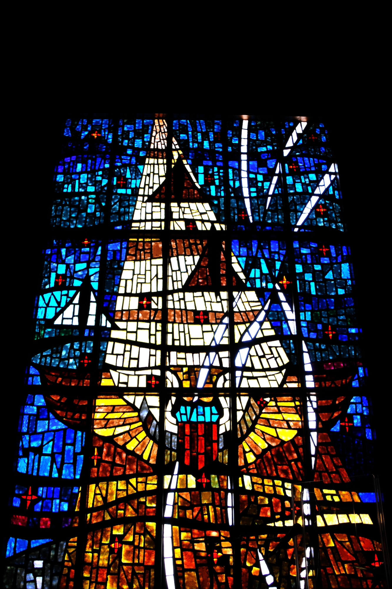 Pictured is the memorial stained glass window at the base chapel on Laughlin Air Force Base, Texas, taken July 29, 2014. The window portrays the missing man formation and is a tribute to wing pilot training personnel who lost their lives in combat or aerial flight accidents while in training or after their departure. The ray of light extending from top to bottom represents God’s concern for all mankind, and the vapor trails represent a continued hope reaching out to prisoners of war and those missing in action. (U.S. Air Force photo/Airman 1st Class Ariel D. Delgado)(Released)