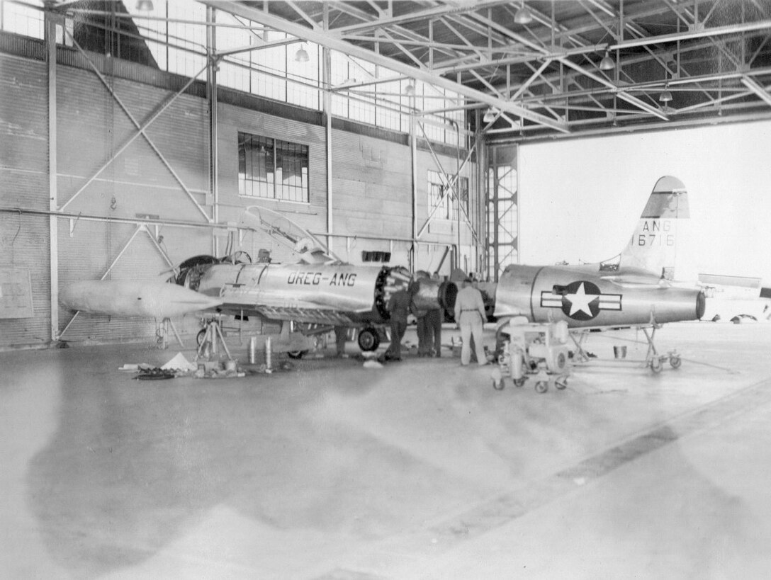 An OreANG Lockheed T-33A-1-LO Shooting Star jet trainer, serial number 51-6716, receives engine work in an aircraft maintenance hangar at Gowen Field during the OreANG’s annual training, June 25, 1954.  (Courtesy 142FW History Archives)