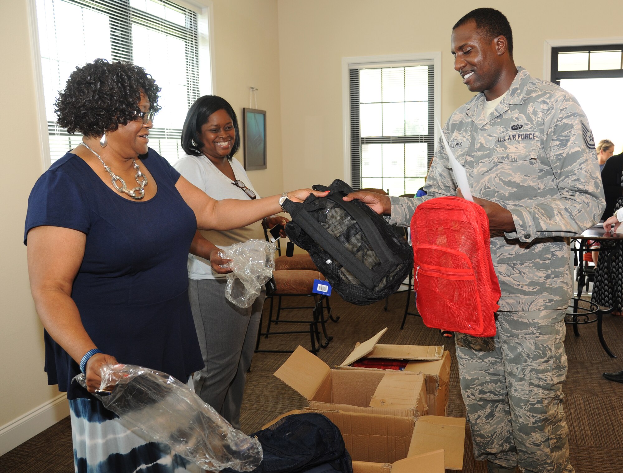 YoLanda Wallace, 81st Infrastructure Division military family housing, and Michelle Thames, Forest City representative, pass out book bags to Tech. Sgt. Quan Holmes, 336th Training Squadron, during a backpack and school supplies give-away event July 29, 2014, at the Bay Ridge Community Center, Keesler Air Force Base, Miss.  The 81st Force Support Squadron and Operation Home Front partnered together to host the event for military families.  (U.S. Air Force photo by Kemberly Groue)