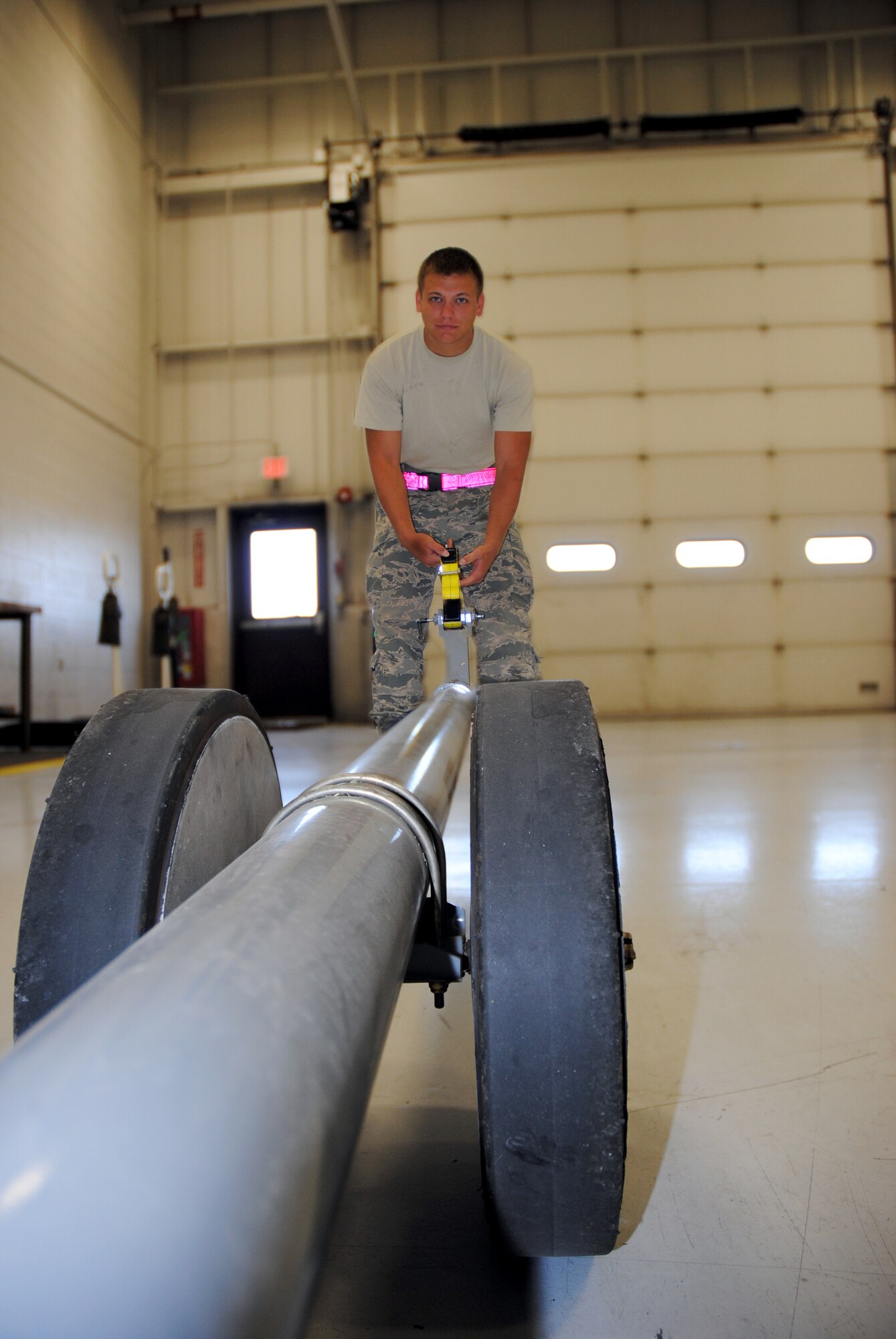 Senior Airman Jacob Schmoltze, 69th Maintenance Squadron Aerospace Ground Equipment mechanic, inspects the ratchet strap clamp for an RQ-4 Global Hawk tow bar by checking for rips and loss of tension July 28, 2014, in the Aerospace Ground Equipment shop on Grand Forks Air Force Base, N.D. The tow bar is hooked up to the tow truck before it is connected to a parked aircraft. (U.S. Air Force photo/Staff Sgt. Luis Loza Gutierrez)