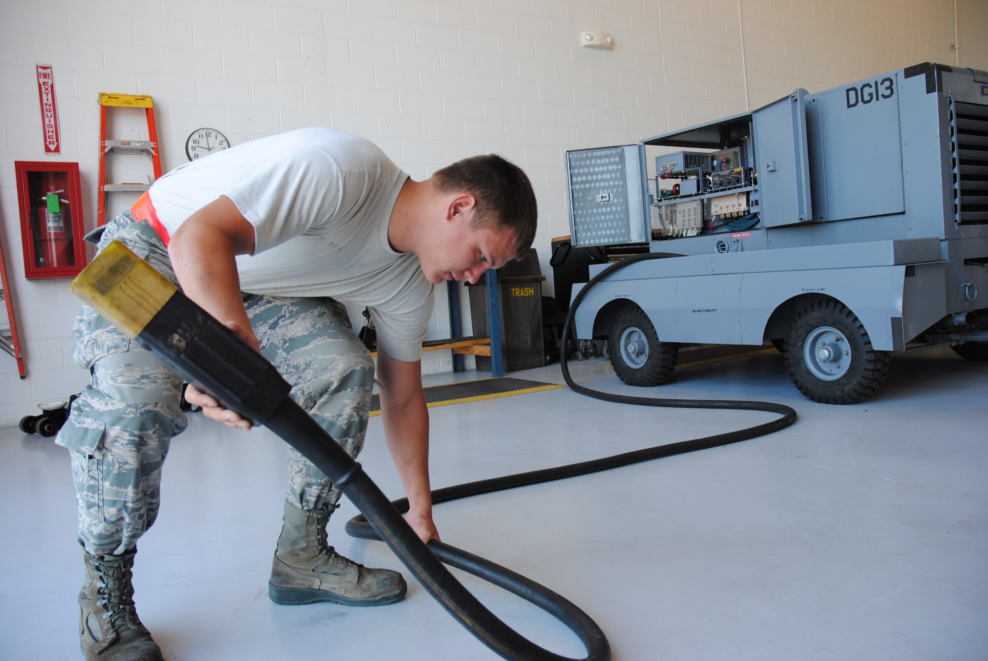 Senior Airman Jacob Schmoltze, 69th Maintenance Squadron Aerospace Ground Equipment mechanic, lifts the 50 pound power cable of a mobile generator July 28, 2014, in the Aerospace Ground Equipment shop on Grand Forks Air Force Base, N.D. Mobile generators are sometimes used to provide electric power to aircraft during repairs. (U.S. Air Force photo/Staff Sgt. Luis Loza Gutierrez)
