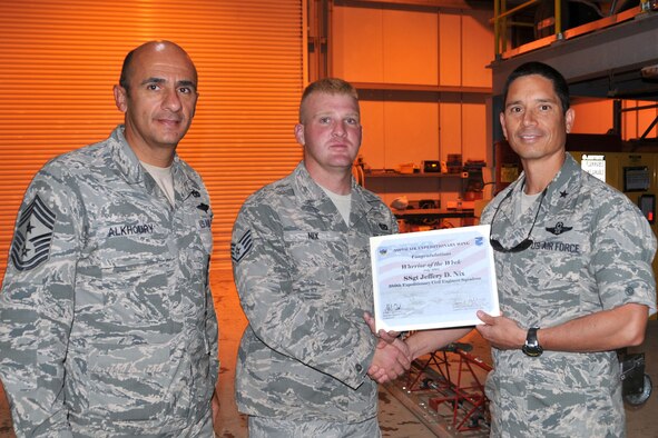 Air Force Brig. Gen. John Quintas, 380th Air Expeditionary Wing commander, and Chief Master Sgt. Samer Alkhoury, 380th Air Expeditionary Wing command chief, present Air Force Staff Sgt. Jeffery Nix, 380th Expeditionary Civil Engineer Squadron pavement and equipment craftsman, a warrior of the week certificate at an undisclosed location in Southwest Asia, July 30, 2014. Nix is deployed from Andrews Air Force Base, Maryland. (U.S. Air Force photo by Senior Master Sgt. Eric Peterson/Released