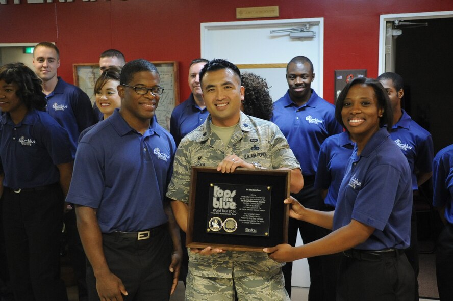 Staff Sgt. Marc Hightower, Tops in Blue keyboard player, and Capt. Fanesha Friar, Tops in Blue Officer in Charge, present an appreciation plaque to 18th Air Maintence Squadron commander, Lt. Col. John Tran at Kadena Air Base, Japan, July 28, 2014. The plaque is to recognize Hightower's releasing squadron for their support of Hightower's role in Tops in Blue. (U.S. Air Force photo by Airman 1st Class Zackary A. Henry/Released)