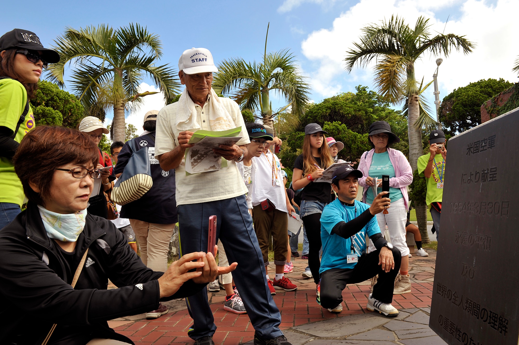 Okinawa City citizens take a picture of a plaque at the Peace Garden memorial during an annual historical site visit on Kadena Air Base, Japan, July 29, 2014. More than 90 people from Okinawa City and nine students from Toyonaka City, Osaka, visited three war-related sites on Kadena. Okinawa City organizations and citizens visit during this time period every year to learn about significant pieces of history here on Kadena.  (U.S. Air Force photo by Naoto Anazawa/Released)