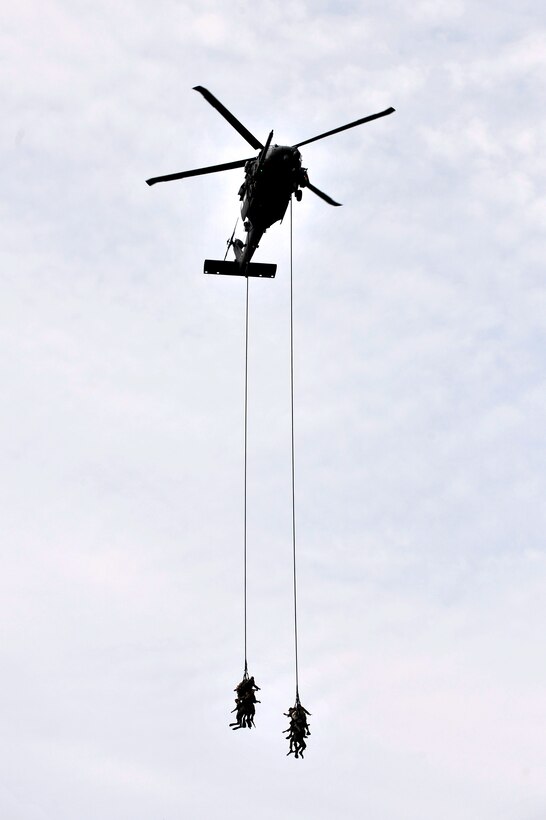 An HH-60 Pave Hawk helicopter hoists soldiers on a fast-rope line during insertion and extraction training off the coast of Long Island, New York, July 24, 2014.