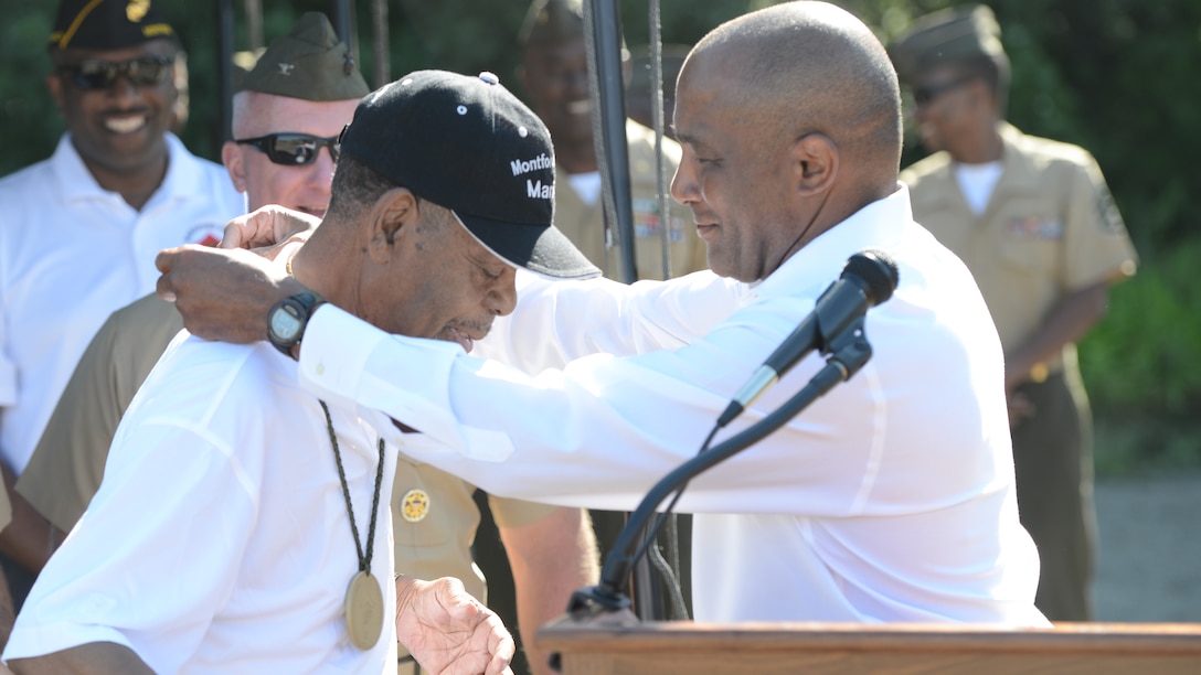 Ronald S. Coleman, a retired Marine lieutenant general, presents Richard H. Walker, a retired Marine gunnery sergeant trained at Camp Gilbert H. Johnson formerly known as Montford Point, a medal during the 2nd Annual Montford Point Biathlon at Marine Corps Base Quantico, Virginia, July 25, 2014. 
