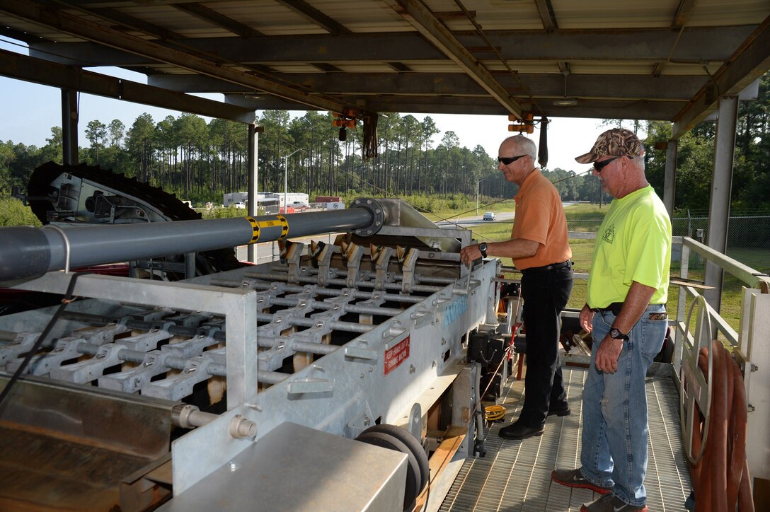 John Fondren, supervisory chemist, Industrial Waste Treatment Plant, Public Works, Installation and Environment Division, (left), evaluates sludge dewatering on the IWTP’s belt press as Steve Nelson, industrial waste water operator, IWTP, Public Works, I&E Division, looks on. The belt press thoroughly removes water from waste sludge prior to disposal offsite.