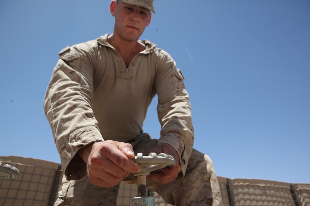 Corporal Marc-Anthony Diplacido, a water support technician with Combat Logistics Battalion 7, opens a valve to a water bladder during a daily inspection aboard Camp Dwyer, Helmand province, Afghanistan, July 21, 2014. Water support technician Marines produce approximately 50,000 gallons of water each day to support coalition forces stationed aboard Camp Dwyer. (U.S. Marine Corps photo by Cpl. Cody Haas/ Released)