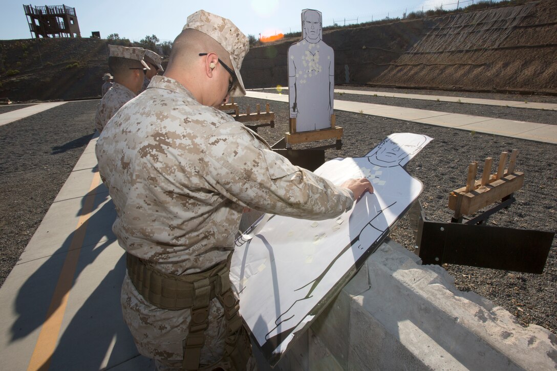 Staff Sgt. Juan Carrillo, a drill instructor with Receiving Company, Support Battalion, Marine Corps Recruit Depot San Diego, puts stickers over round holes on his target after firing an M9 Berretta pistol at Carlos Hathcock Range Complex aboard Marine Corps Air Station Miramar, Calif., July 29. Marines shooting the pistol are now required to qualify using the Corps’ newest pistol program, the Combat Pistol Program.