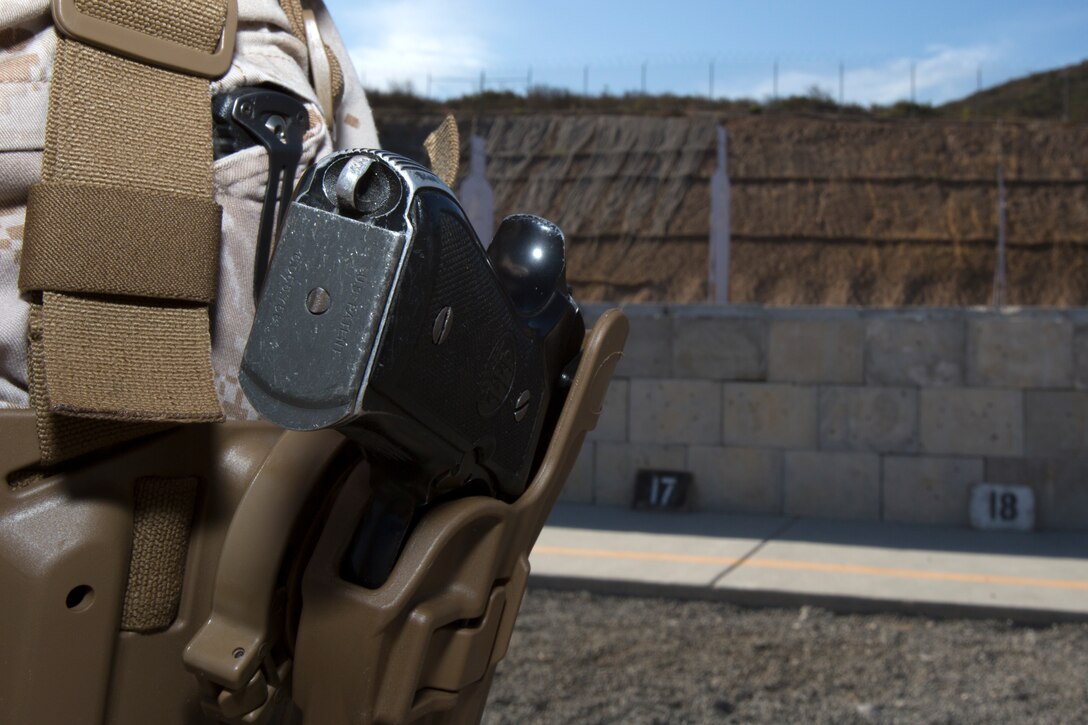 An M9 Berretta pistol is secured in a holster during a training event at Carlos Hathcock Range Complex aboard Marine Corps Air Station Miramar, Calif., July 29. The new Combat Pistol Program requires shooters to draw their M9 Berretta pistol from a holster, fire at a target, and hold their pistol in a ready position while assessing the area around them for more threats.