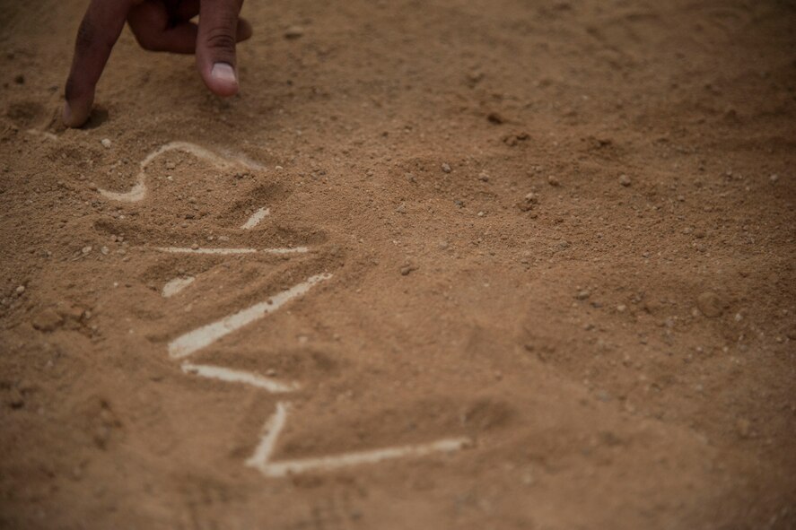 A member of the 8th Maintenance Squadron Dragons writes the teams name on the field after the squadron championship softball game at Kunsan Air Base, Republic of Korea, July 30, 2014. The game’s final score ended with the Dragons taking the win, 14 to 9. (U.S. Air Force photo by Staff Sgt. Jose Rodriguez/Released)