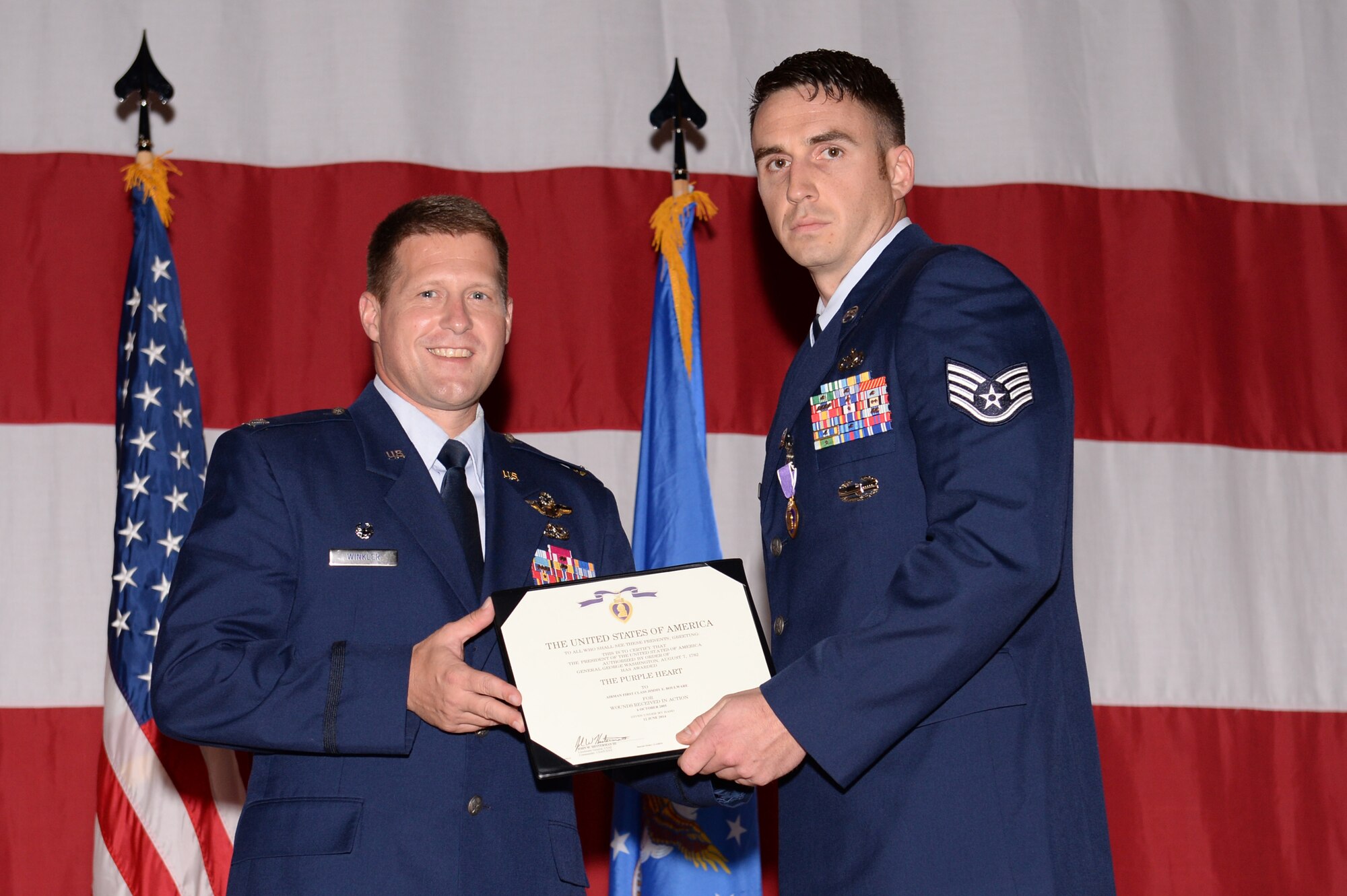 U.S. Air Force Staff Sgt. Jimmy Boulware, 354th Logistics Readiness Squadron vehicle operator, receives a Purple Heart decoration from Col. Michael Winkler, 354th Fighter Wing commander, during a promotion recognition ceremony at the base theater July 31, 2014, Eielson Air Force Base, Alaska.  Boulware sustained injuries from an improvised explosive device during a 2005 deployment to Iraq. (U.S. Air Force photo by Senior Airman Peter Reft/Released)  