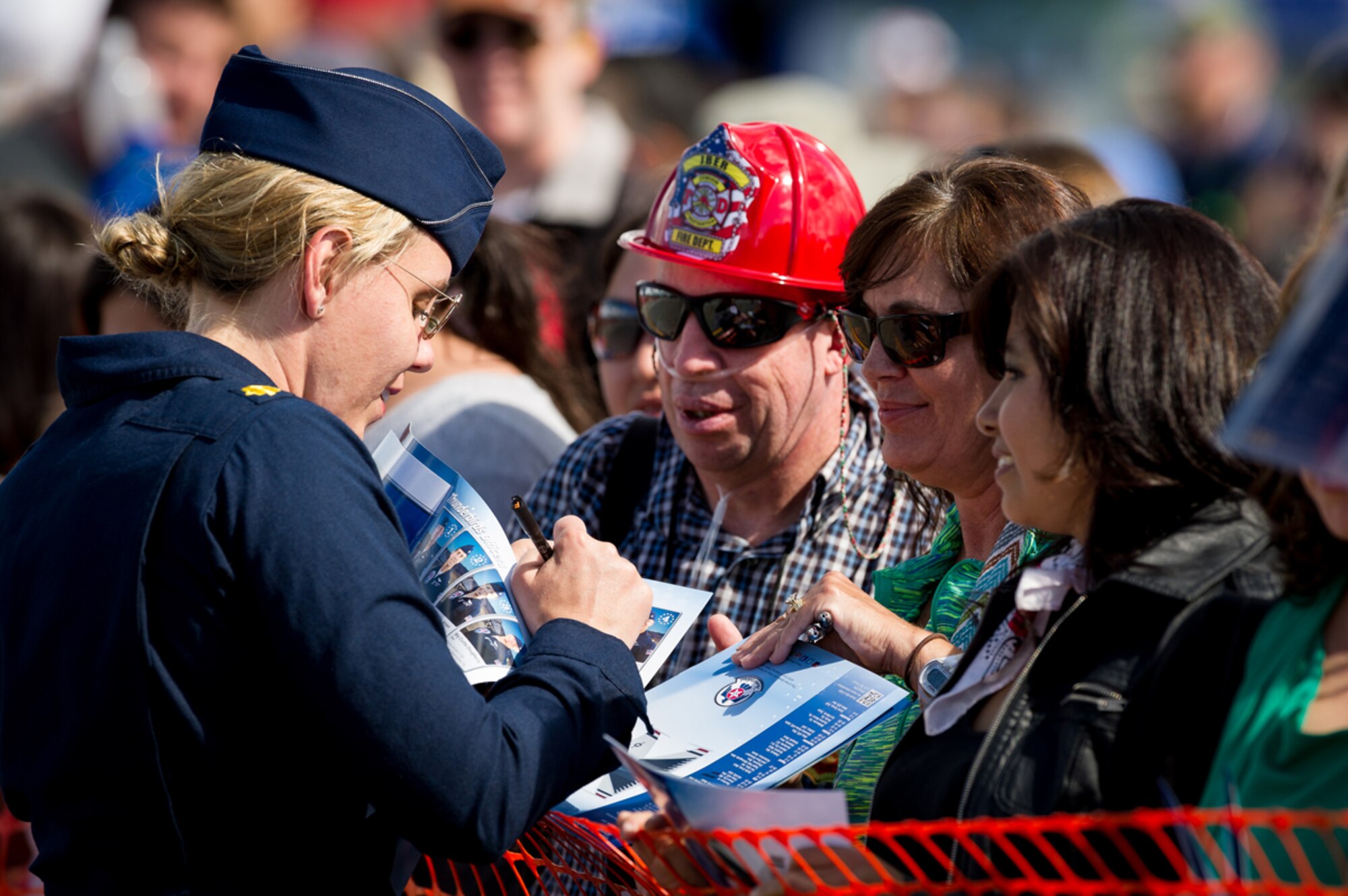 The U.S. Air Force Thunderbirds Maj. Caroline Jensen, Thunderbird 3, Right Wing, signs a poster for fans following the performance at the Arctic Thunder Open House biennial event hosted by Joint Base Elmendorf-Richardson, Alaska, July 26, 2014. Arctic Thunder is a biennial event hosted by JBER. Featuring more than 40 Air Force, Army and civilian aerial acts and an expected crowd of more than 200,000 people, it is the largest two-day event in the state and one of the premier aerial demonstrations in the world. The 2014 Arctic Thunder Open House is a proud part of the Anchorage Centennial Celebration. (U.S. Air Force photo by Master Sgt. John R. Nimmo, Sr./Released)