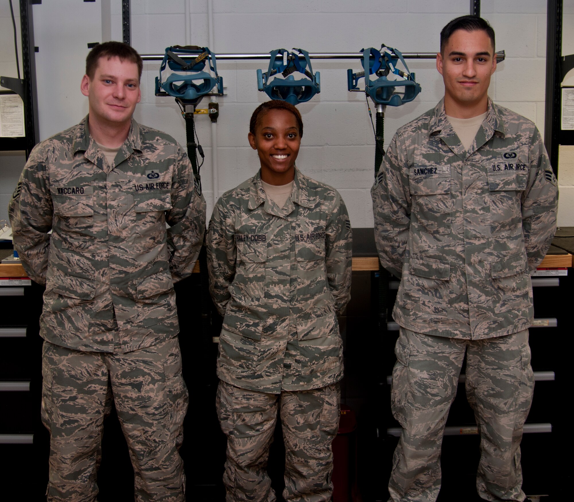 (From left to right) Staff Sgt. Keith Vaccaro, Senior Airman Dominique Hailey-Cobb and Senior Airman Abraham Sanchez, all from the 60th Operations Support Squadron, pose for a group photo July 24, 2014. Tasked with writing the guidelines for the mask inspection and maintenance process, Vaccaro and his technicians, Sanchez and S Hailey-Cobb, meticulously outlined and photographed the step-by-step instructions to diagnose and repair common issues associated with the aging equipment. (U.S. Air Force photo by Senior Airman Charles Rivezzo)