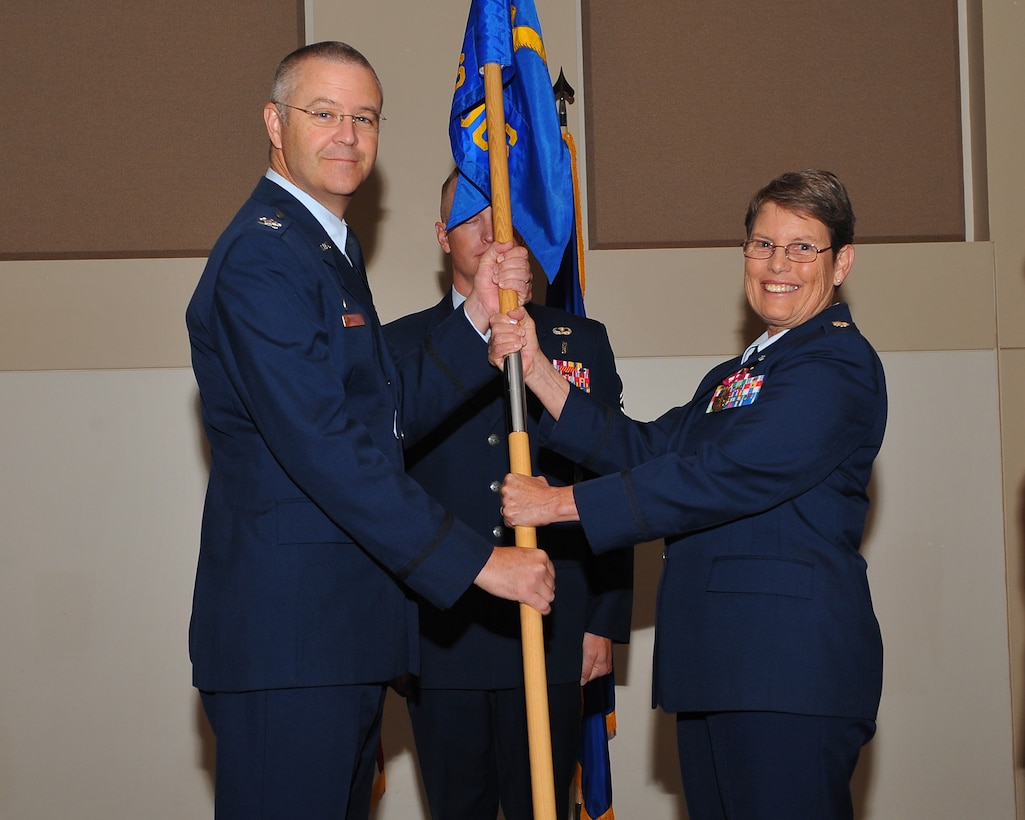 Col. Michael Kindt, 460th Medical Group commander, left, receives the 460th Medical Operations Squadron guidon from Lt. Col. Phyllis Jones, right, symbolizing her relinquishing command during a change of command ceremony July 31, 2014, at the Leadership Development Center on Buckley Air Force Base, Colo. Jones is leaving the 460th MDOS after serving as the unit’s commander for three years, working through many challenges, including the transitioning of facilities, providing medical care during the Aurora Theater Shooting, and changing the way heath care is provided on base. (U.S. Air Force photo by Senior Airman Phillip Houk/Released)